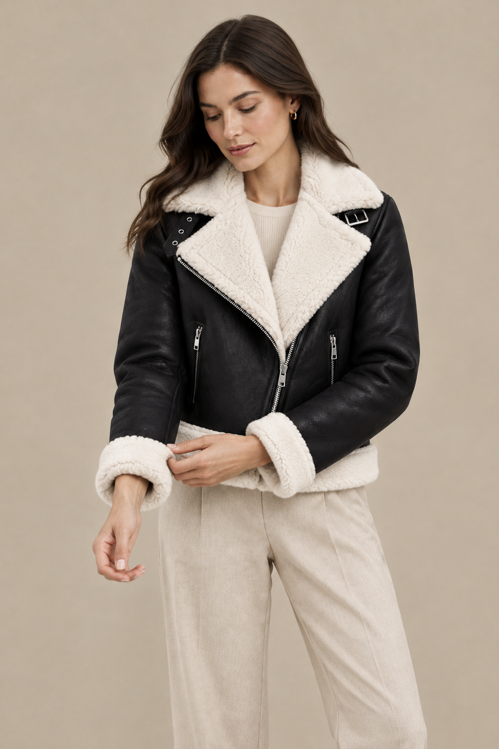 Modelo con chaqueta Laia ajustándose el puño sobre fondo arena
